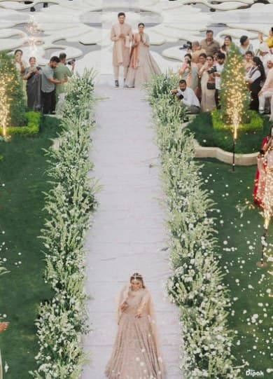 Bride walking down a white aisle lined with white wildflowers and sparklers