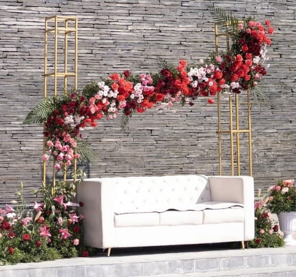Gold frames with a cascade of red and pink roses over a white sofa