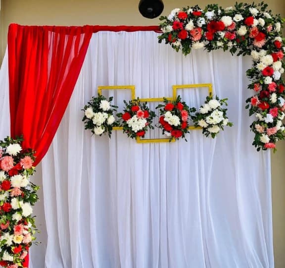 White drape backdrop with a red swag and red and white floral corners