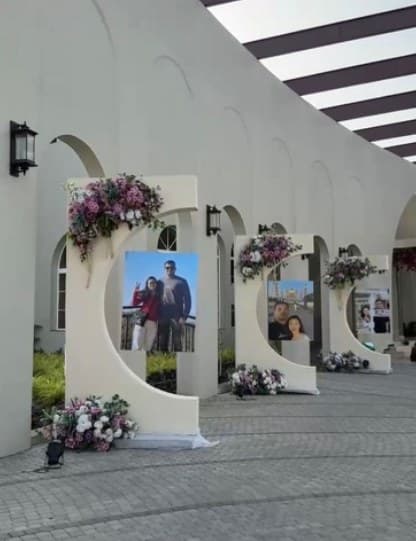 Row of cream arched frames with couple photos and flowers along a walkway