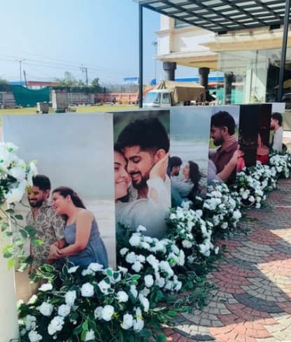 Line of couple photo panels along a path edged with white roses