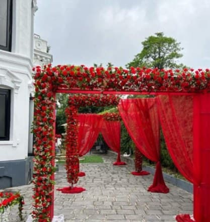 Series of red rose frames with red drapes along a stone courtyard path