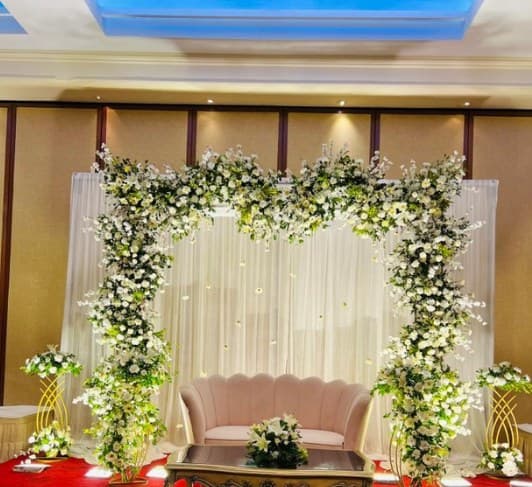 Square floral frame of white flowers and greenery around a blush sofa and coffee table