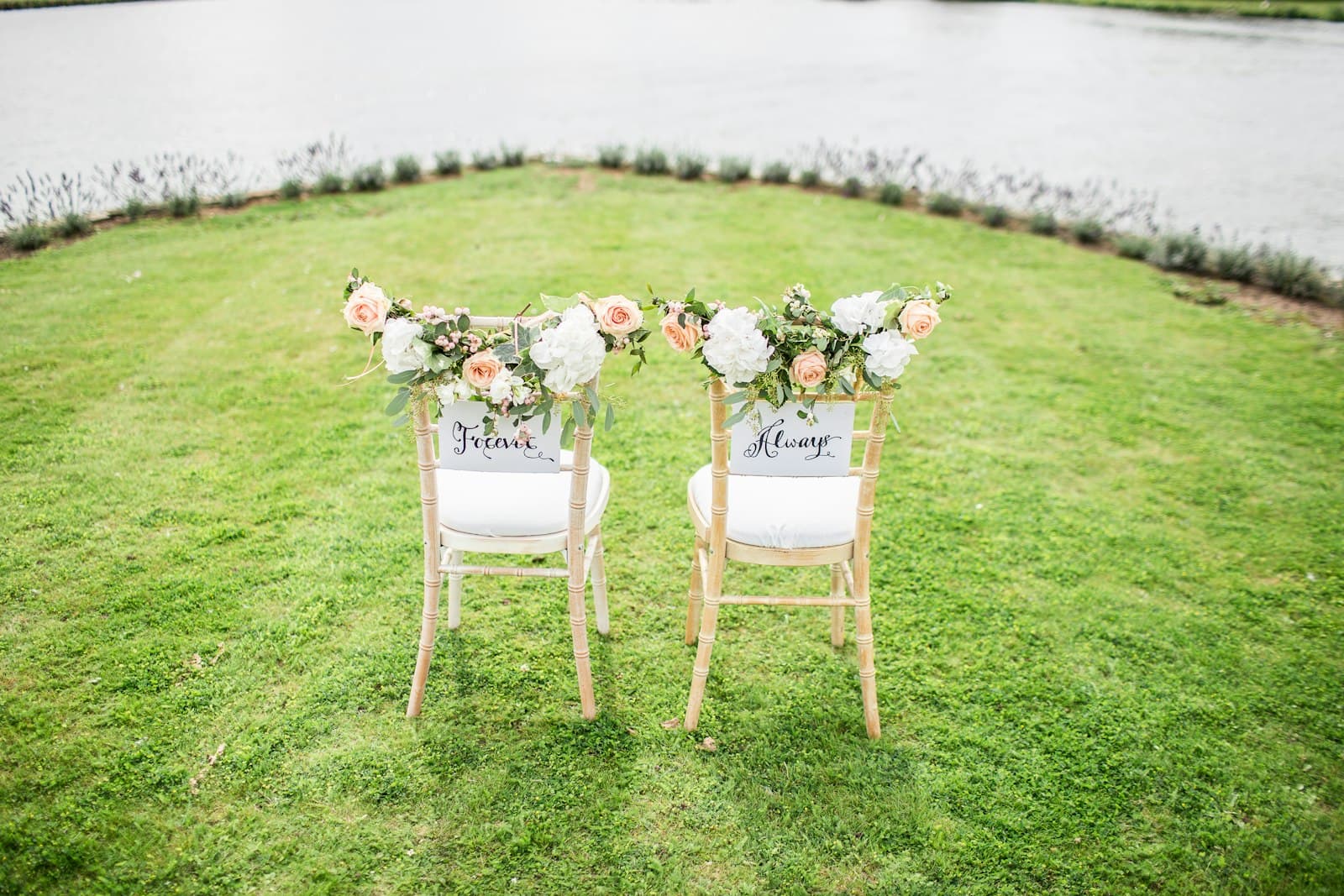 Two chairs decorated with peach roses and signs reading Forever and Always