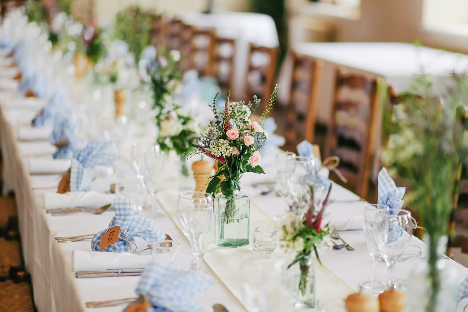 Long dining table styled with flowers, candles and glassware